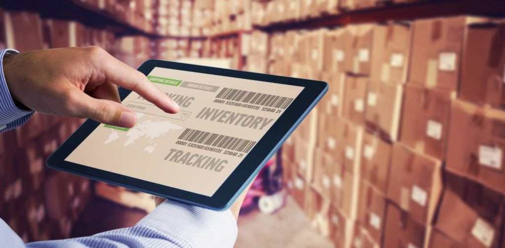 Man using tablet pc  against boxes in warehouse